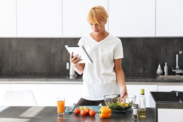 A person reviewing a meal plan on a tablet in a modern, minimalist kitchen, with various containers of pre-prepared ingredients and meals visible on the countertop. The lighting is soft, creating a sense of calm and organization.