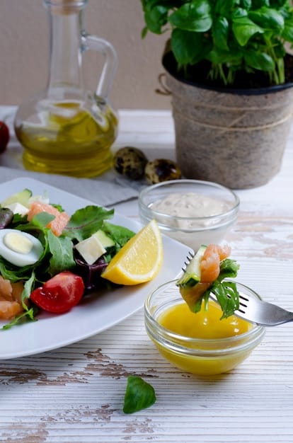 Close-up shot of various healthy salad dressing ingredients: olive oil, balsamic vinegar, lemon, fresh herbs (such as dill and parsley), garlic cloves, and honey. The ingredients are arranged on a wooden cutting board, with sunlight streaming in, highlighting their vibrant colors and textures.