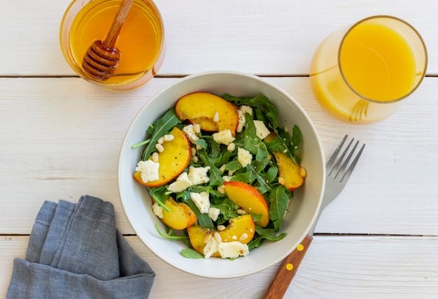 Overhead shot of a colorful grilled peach and arugula salad served in a rustic wooden bowl, garnished with crumbled goat cheese and toasted pecans. A balsamic glaze drizzle adds a touch of elegance.