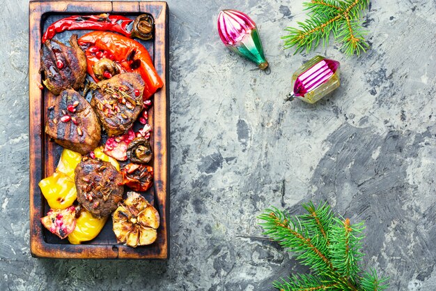 A top-down shot of a grill filled with various marinated meats and vegetables. The meats include chicken skewers, beef steaks, and bell peppers, all displaying vibrant colors and char marks. The grill is set in a backyard environment, with trees and sunlight visible in the background, creating a warm and inviting atmosphere.