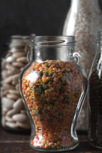 A close-up shot of a variety of dried lentils and beans in clear glass jars, arranged neatly on a pantry shelf, with labels clearly visible, highlighting their affordability and accessibility.