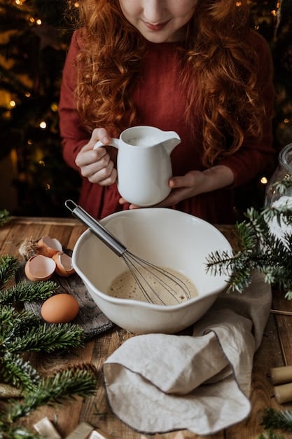 A close-up shot of a baker adding grated apple to a batter in a mixing bowl, with holiday-themed kitchen accessories in the background, emphasizing healthy ingredient swaps in baking.