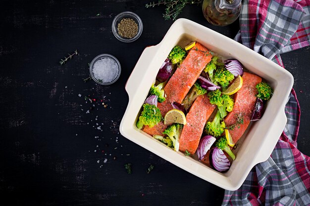 An overhead shot of a baking sheet filled with perfectly baked salmon fillets and an assortment of colorful roasted vegetables, garnished with fresh herbs.