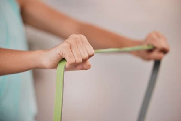A close-up shot of hands holding a resistance band, focusing on the tension and engagement required for a band pull-apart exercise.