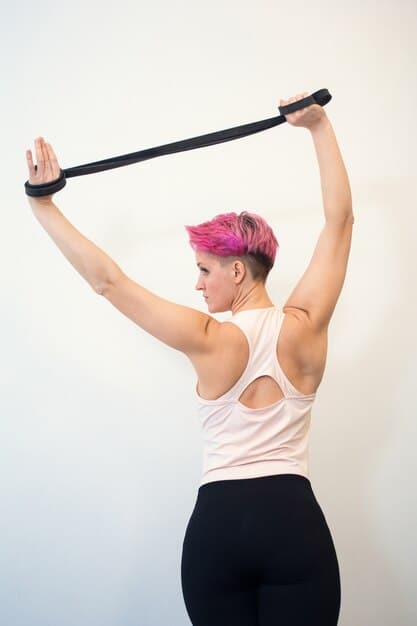 A person performing an overhead tricep extension with a resistance band, focusing on the muscle engagement in the arms.