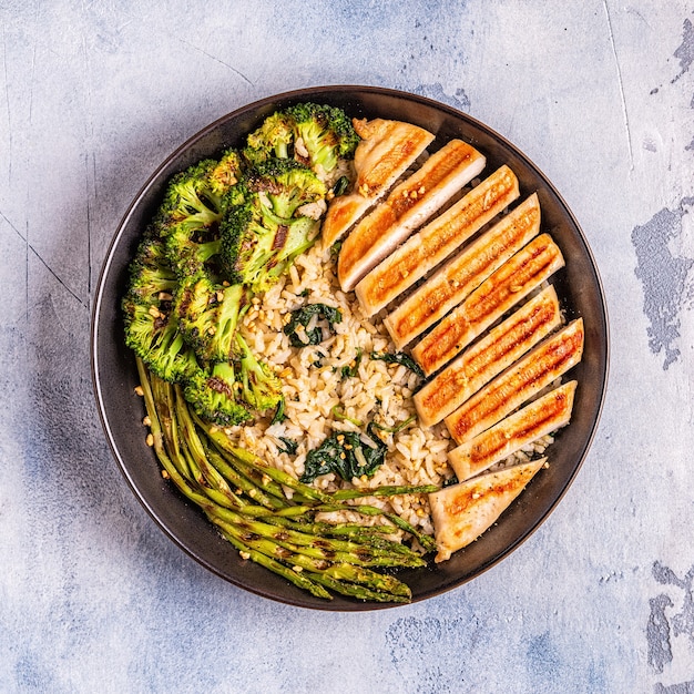A nutritious post-workout meal consisting of grilled chicken breast, brown rice, and steamed broccoli, displayed on a clean, modern plate.