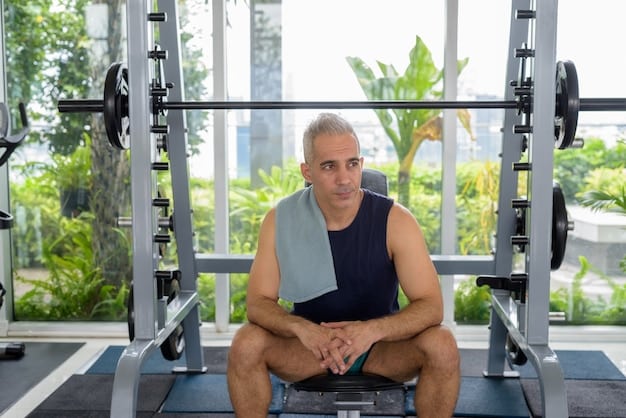 A man in his late 40s is performing a bench press at a gym. He is using proper form and appears focused. A spotter is standing behind him. The gym is well-equipped and has a supportive atmosphere.