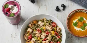 Three healthy post-workout recovery meals laid out on a table, including a smoothie, quinoa bowl, and soup, designed to reduce muscle soreness.